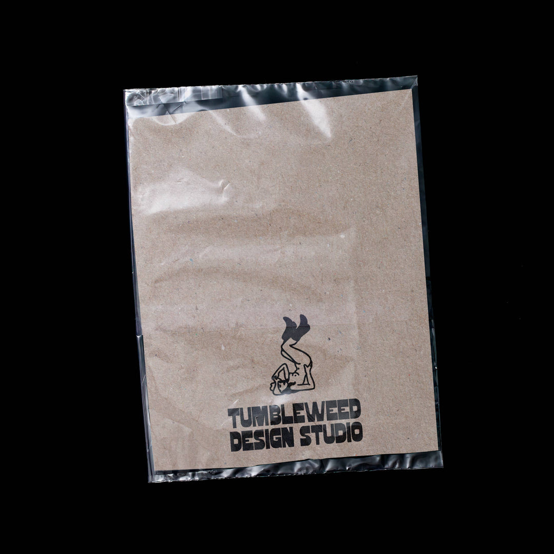 Kraft paper bag with Tumbleweed Design Studio logo on a black background