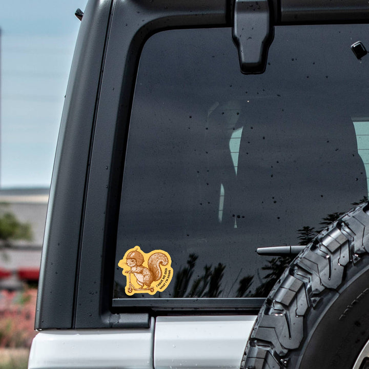 Squirrel-shaped sticker on a car window with a blurred background