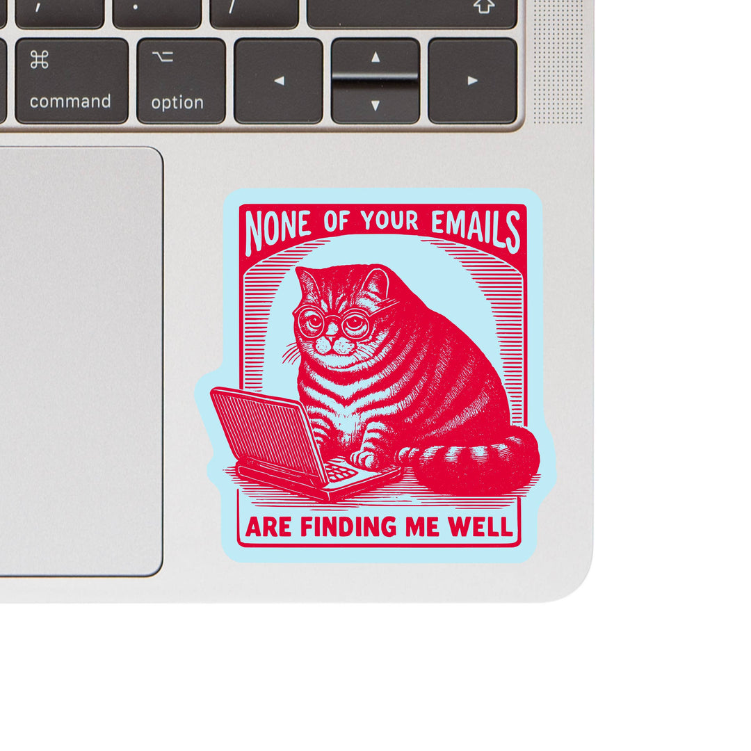 Laptop with a sticker of a cat using a laptop and text 'None of your emails are finding me well'.