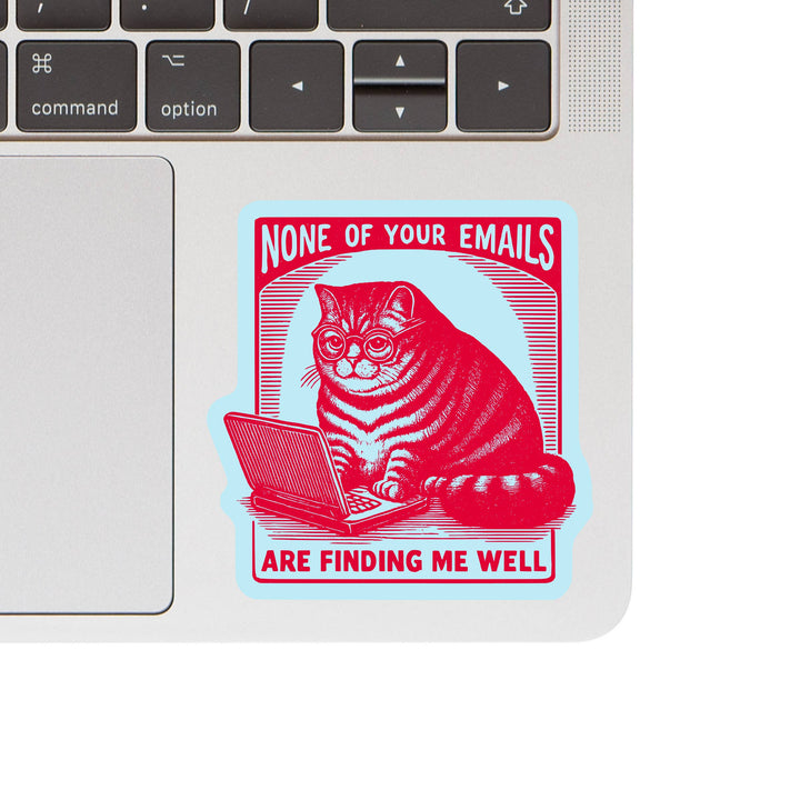 Laptop with a sticker of a cat using a laptop and text 'None of your emails are finding me well'.