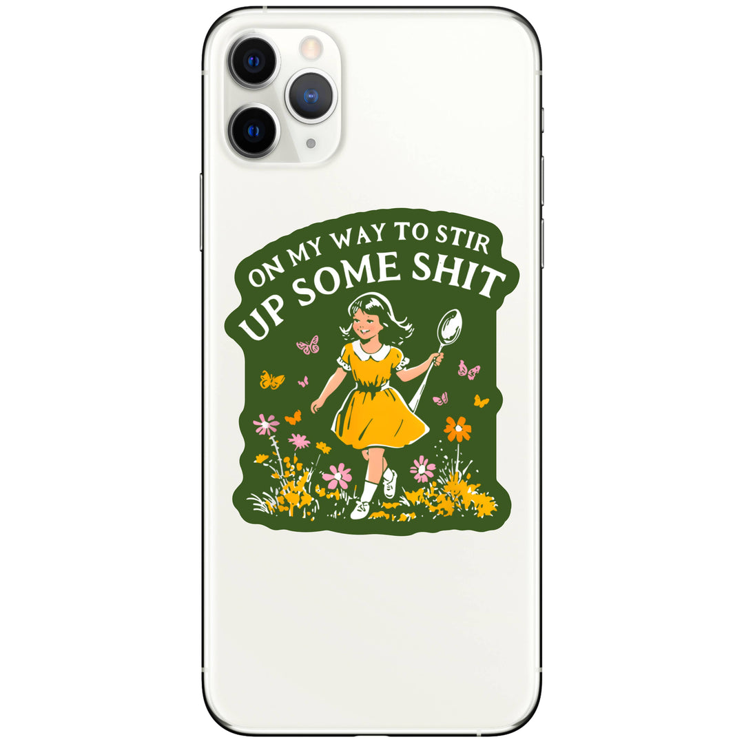Phone case with a design of a girl in a yellow dress holding a spoon, surrounded by flowers and butterflies, with text 'On my way to stir up some shit' on a green background.
