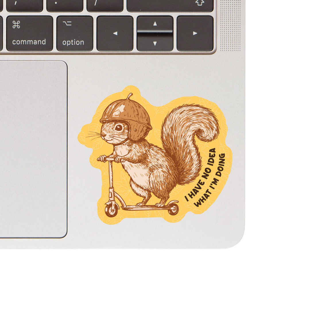 Laptop with a sticker of a squirrel on a scooter and text 'I have no idea what I'm doing' on a white background