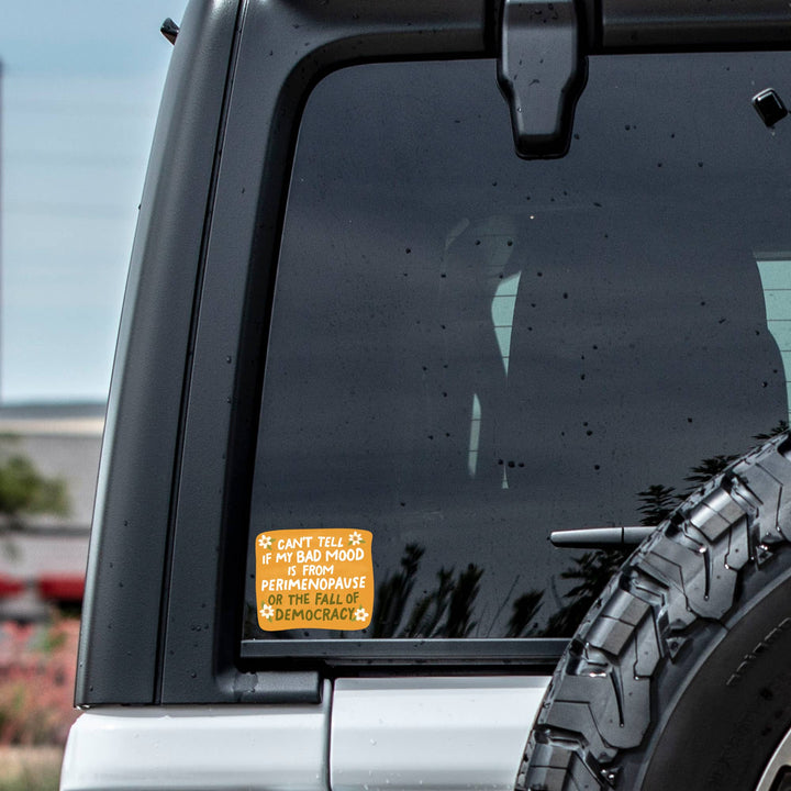 Car window with a sticker and tire visible outdoors