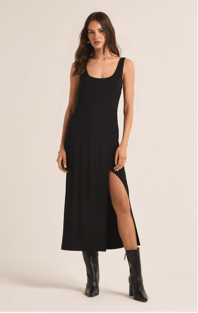 Woman in a Z Supply Z Supply Melbourne Dress with a side slit and black boots standing on a plain background.